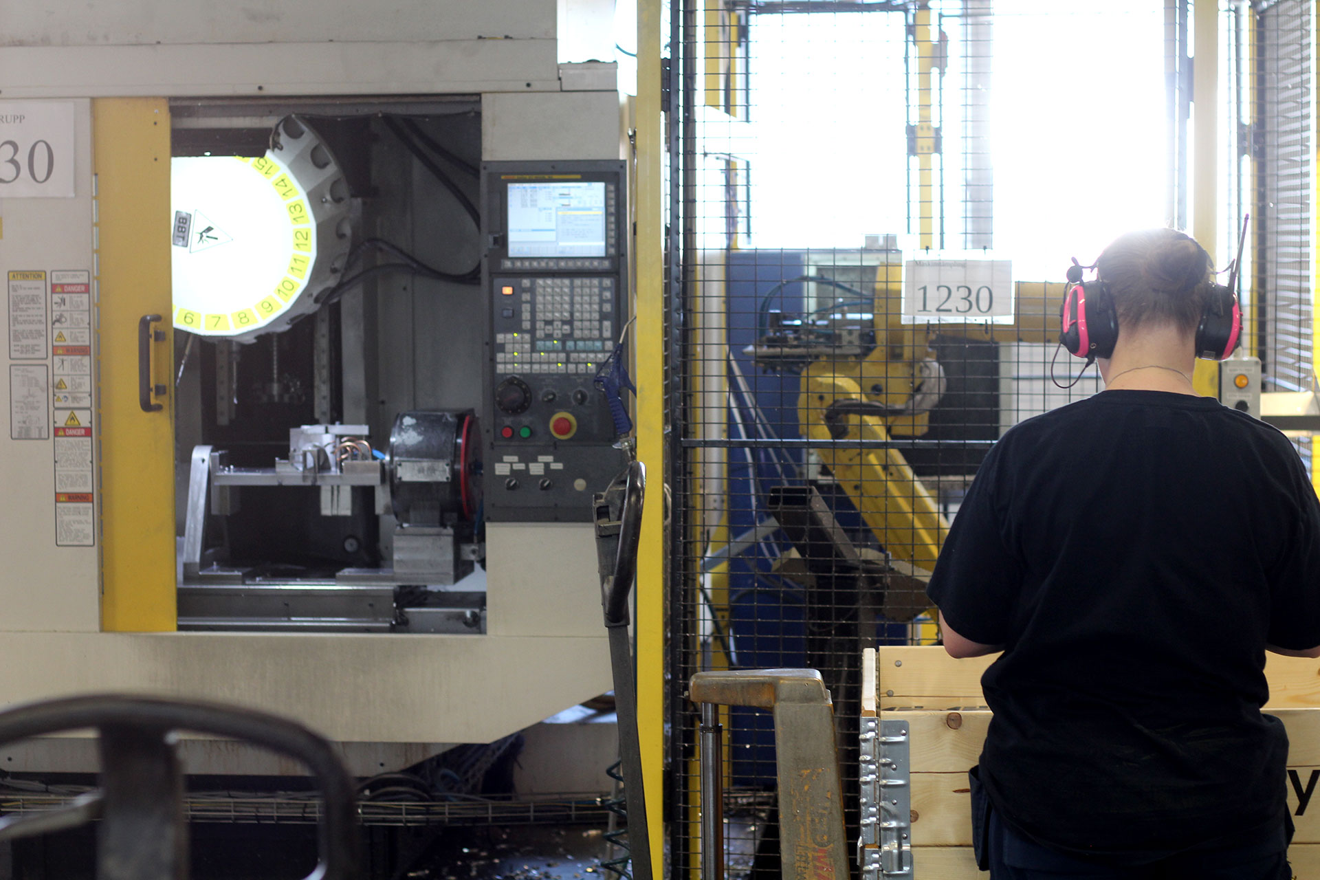 Operat&ouml;r &ouml;vervakar CNC-bearbetning av aluminium i automatiserad produktionscell.